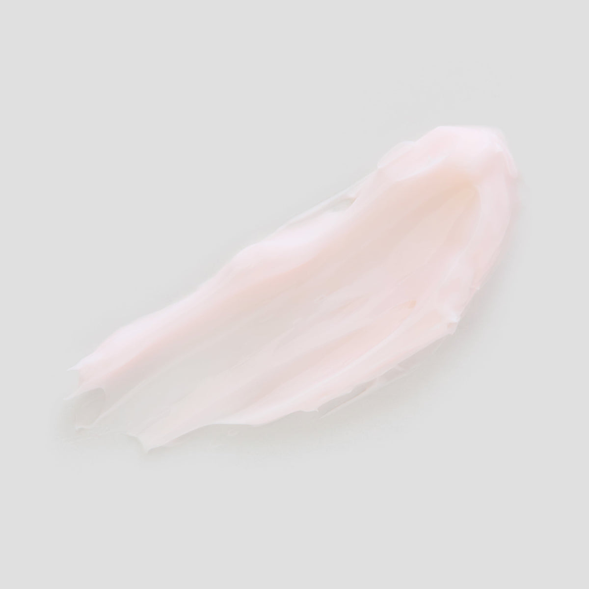 Swatch of light pink moisturizing cream on a light gray background