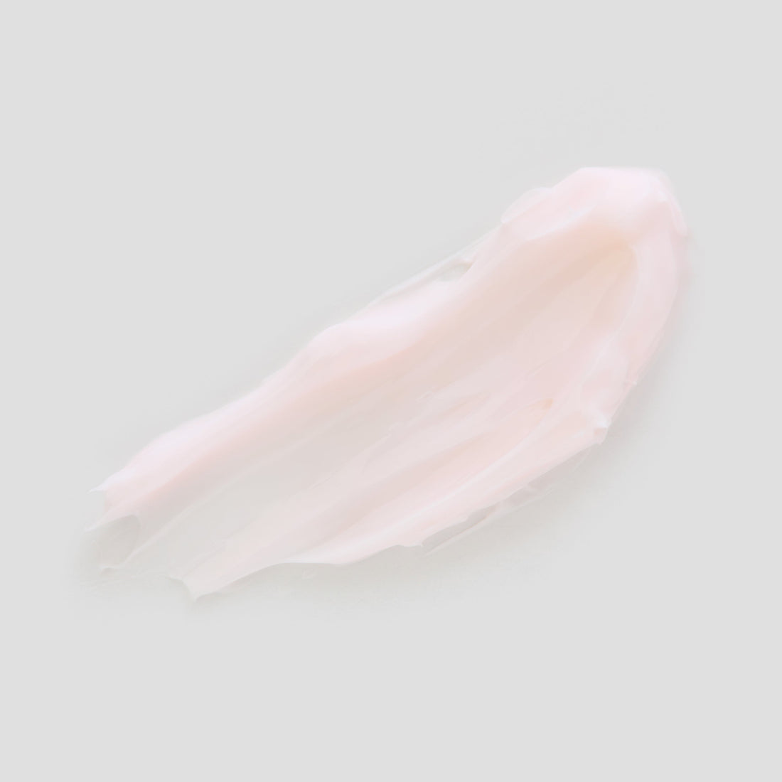 Swatch of light pink moisturizing cream on a light gray background